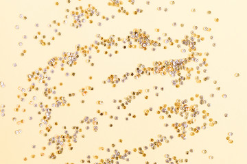 Festive Christmas composition. Shining golden sequins on light pastel background. Christmas. Wedding. Birthday. Flat lay, top view, copy space.