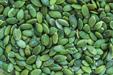 Background in the form of peeled green pumpkin seeds, top view