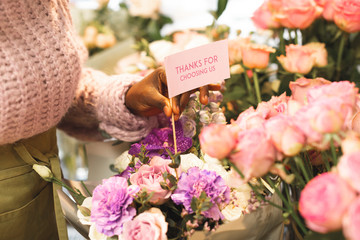 Close up of female hand that putting card into bouquet