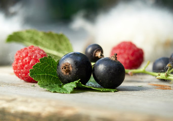 Fresh berries on wooden background. Raspberries and black currants.