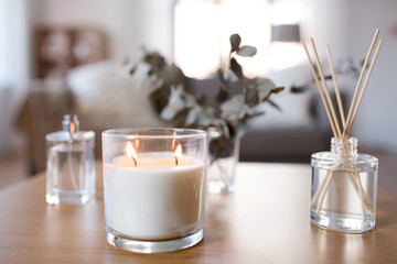 decoration, hygge and aromatherapy concept - aroma reed diffuser, burning candle and perfume on...