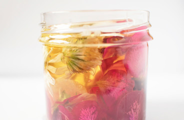 glass bottle oil based on various medicinal herbs and flowers, cosmetic oil for skin care on white background