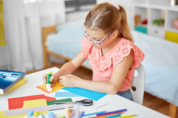 childhood, creativity and hobby concept - creative girl making greeting card and sticking pompon...