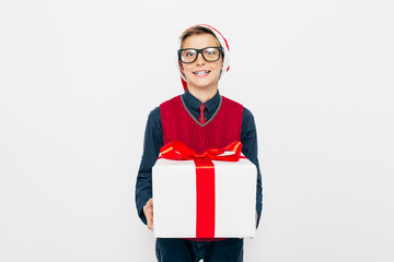 Funny little boy in a red Santa hat. Stylish boy with Christmas gift, on white background.