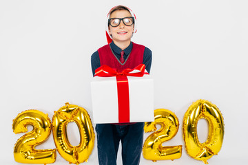 A little boy in a Santa hat, a stylish child with a Christmas gift in his hands, on a white...