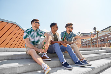 Fototapeta premium leisure, technology and people concept - happy male friends taking selfie by smartphone on tripod and drinking beer on street in summer