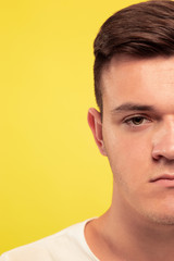 Fototapeta premium Caucasian young man's close up portrait on yellow studio background. Beautiful male model with well-kept skin. Concept of human emotions, facial expression, sales, ad. Looks sad and upset.