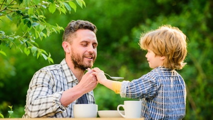 Natural nutrition concept. Feeding son natural foods. Stage of development. Feed son solids. Dad and boy eat and feed each other outdoors. Ways to develop healthy eating habits. Feed your baby