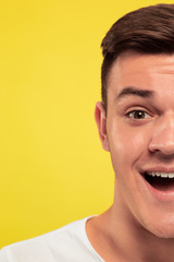 Caucasian young man's close up portrait on yellow studio background. Beautiful male model with well-kept skin. Concept of human emotions, facial expression, sales, ad. Looks happy and smiling.
