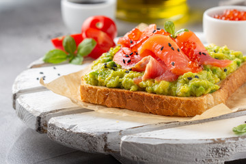 Toast with avocado, red fish (salmon, trout), caviar and black sesame. Tasty, bright, delicious healthy breakfast or lunch