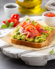 Toast with avocado, red fish (salmon, trout), caviar and black sesame. Tasty, bright, delicious healthy breakfast or lunch