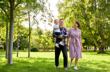 Fototapeta premium family, leisure and people concept - happy mother, father and little son at summer park