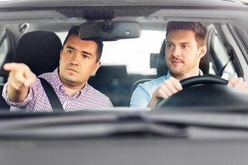driver courses and people concept - car driving school instructor teaching young man to drive