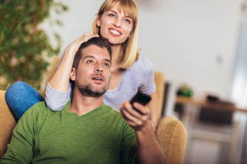 Fototapeta premium Young couple watching TV on a sofa at home