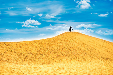 Fototapeta na wymiar Sandy landscape with silhouette woman on top of dune. Natural reserve Maspalomas Dunes, Gran Canaria, Spain