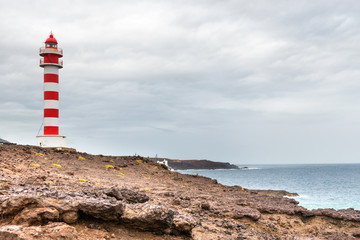 Striped red and white lighthouse at rocky coast of Gran Canaria island, Spain