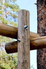 Three Cracked Wooden Log Fastened Perpendicularly to Each Other with New Shiny Bolt with Two Nuts