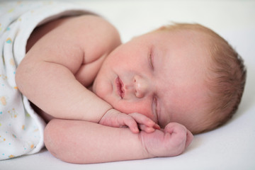 Close up of a cute sleeping baby resting on their arms