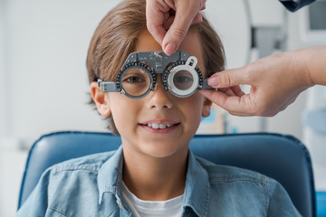 Young boy with phoropter during sight testing eye examinations in ophthalmological clinic....