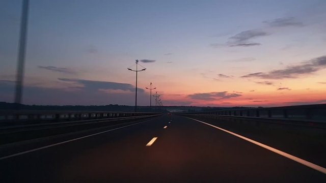 Driving on highway at sunrise. View through the front window car. Driver point of view. Road travel concept