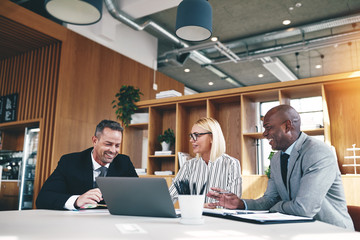 Three diverse businesspeople laughing while working together in