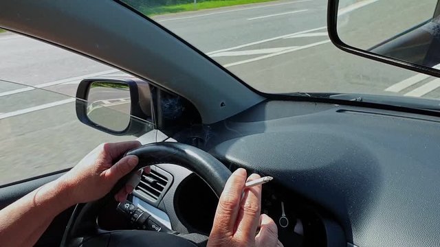 Smoking Cigarette In The Hand Of Woman At Steering Wheel