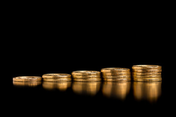 Coins in a stack to increase. A stack of gold coins on a black background.