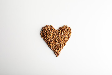 healthy food. Heart shape made from buckwheat grains on white background. Top view. copy space