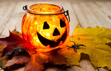 Halloween concept. Jack-o-lantern candle holder with pumpkins, spiders, leaves on wooden background