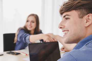 Obraz premium Happy smiling handsome caucasian businessman and businesswoman casual wear shaking hands sitting on desk in modern office, Welcome to team Meeting, negotiation, greeting business Partnership