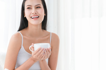 Healthy young beautiful woman smile happy use two hand to hold a cup of coffee on bedroom in morning