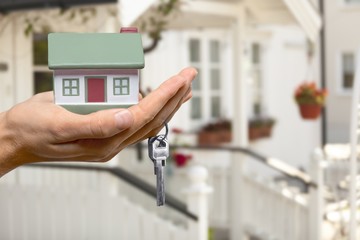 Building, mortgage, real estate and property concept - close up of hand holding house model