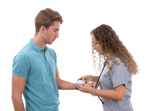 Caucasian young nurse girl with glasses taking blood pressure to a patient with a tensiometer in background isolated