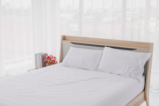 White bedroom interior with windows. Clean white bed and pillows in room.