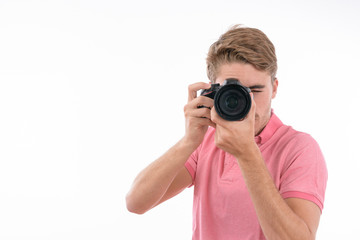 Young Caucasian man taking pictures with photo camera on isolated white background