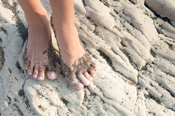 Beautiful female food with beach sand on a white beach rocky surface