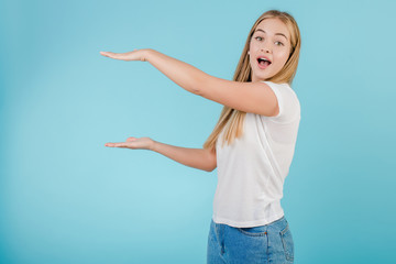 excited woman holding copyspace between her hands isolated over blue