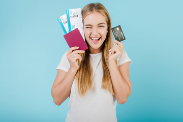 beautiful young blonde girl with passport and credit card isolated over blue