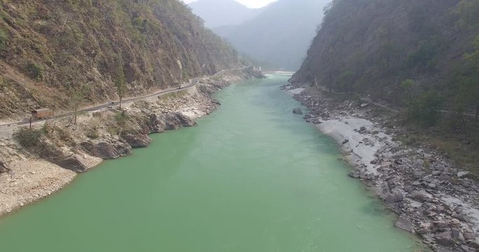 Aerial view of the river Ganges near Rishikesh with a highway with trucks on the left side in India.