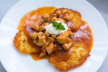 Tasty dinner on a plate of hash browns with sauce and chicken