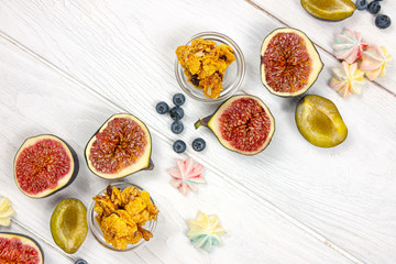 Fresh sliced figs with granola, blueberry, meringues and plums as autumn food background. Flat lay