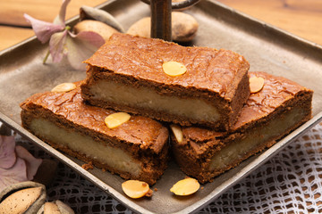 Fresh baked Dutch filled spicy cookies with almonds in autumn colors on dark wooden background
