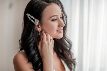 close up. girl bride trying on earrings.