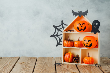 Halloween holiday concept with jack o lantern, house and pumpkin decorations on wooden table
