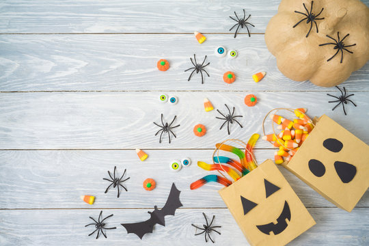 Halloween Holiday Party Background With Gift Paper Bags And Candy .Top View From Above. Flat Lay