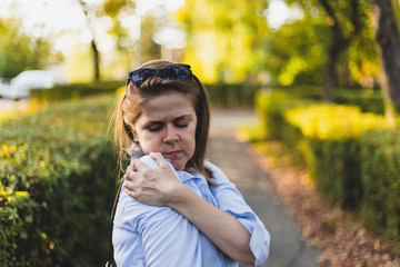 Young woman holding one hand on painful shoulder