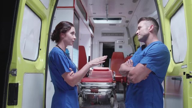 Nurse talk to corpsman over ambulance car at night.