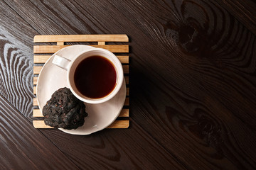 A Cup of Tamarind tea (or Date Tea), saucer, dry ball from the seeds and resins of Indian tamarind on a brown table. Exotic drink on a natural wooden background with copy space