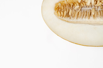 Fresh half sliced yellow melon with seeds on white background in corner