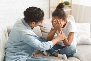 Teenaged girl comforting her crying little sister